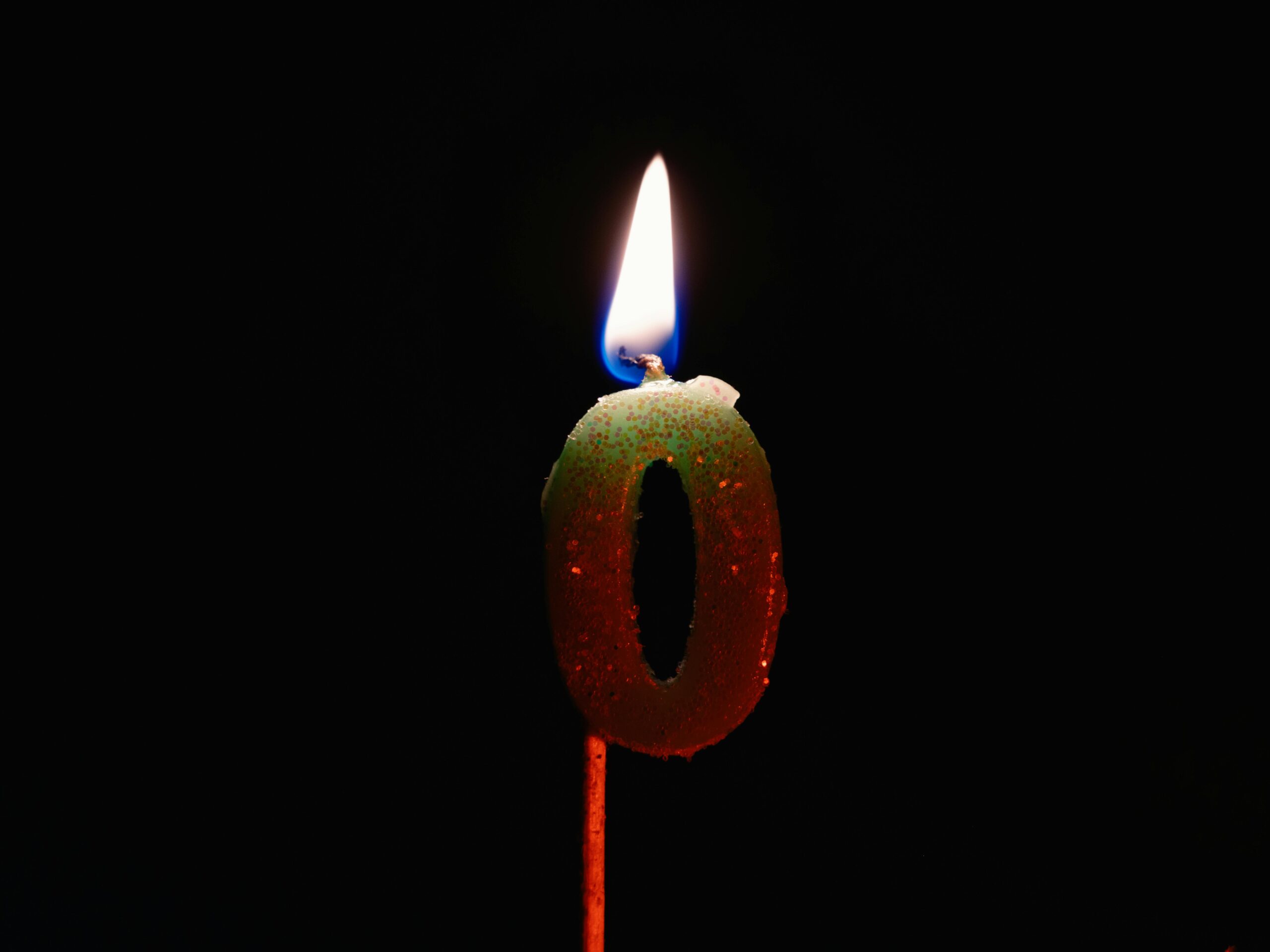Close-up of a number zero candle burning against a dark background.