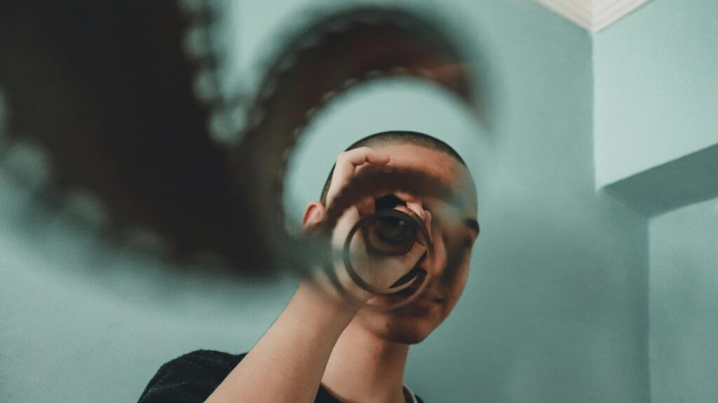 Artistic portrait of a person indoors using a vintage film reel for reflection and visual effect.